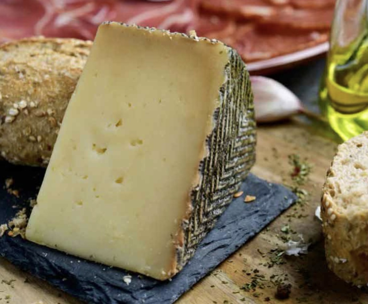 Fromage Manchego présenté avec du pain et de la charcuterie